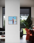 Framed artwork on a white wall in a modern living room with orange chairs and large windows.