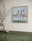 Framed artwork of three people on a wall above a green cabinet with decorative branches.