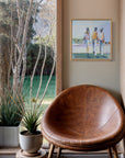 Brown leather chair in a room with a painting on the wall and a view of trees and water outside.