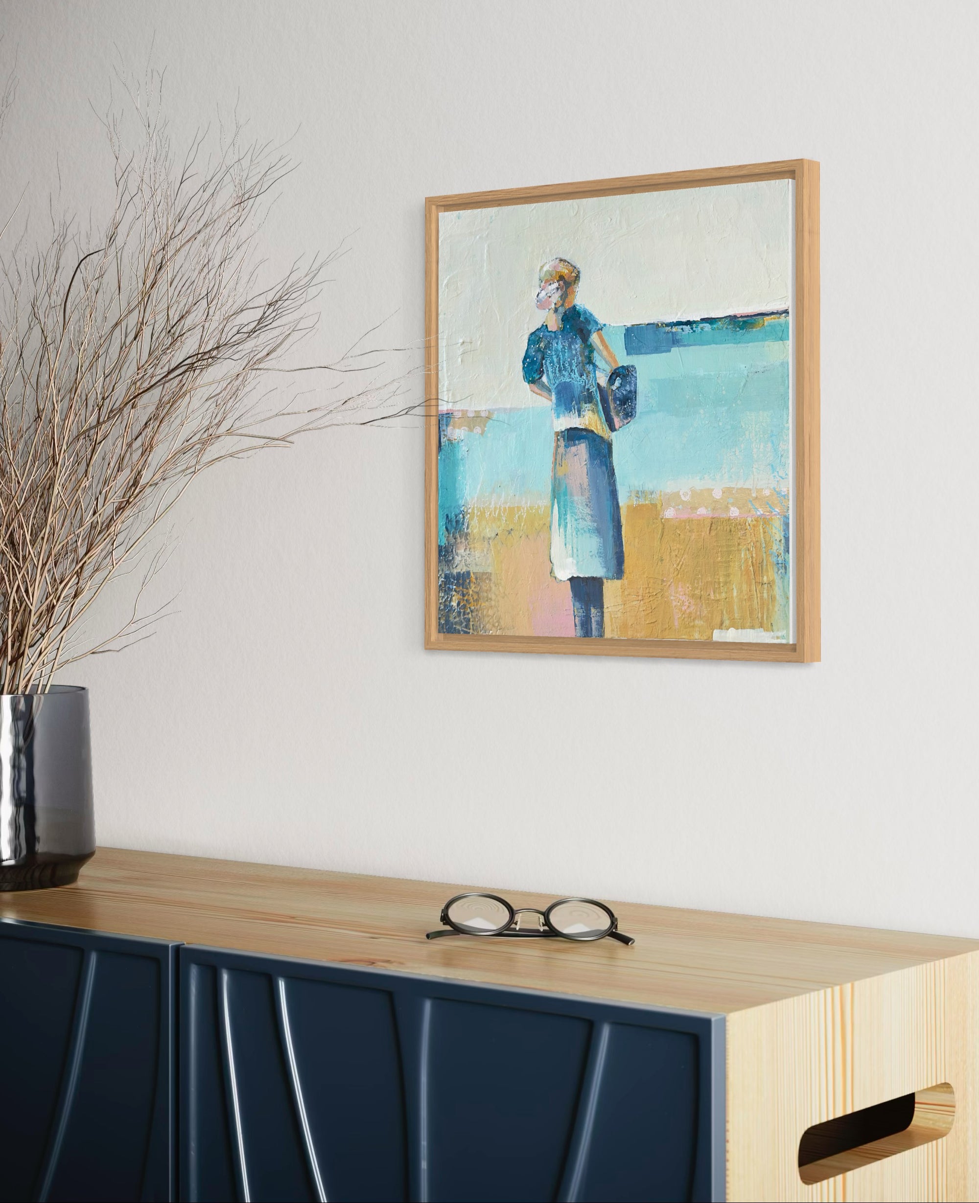 Framed artwork of a woman in a blue dress on a wall above a console table with decorative elements.