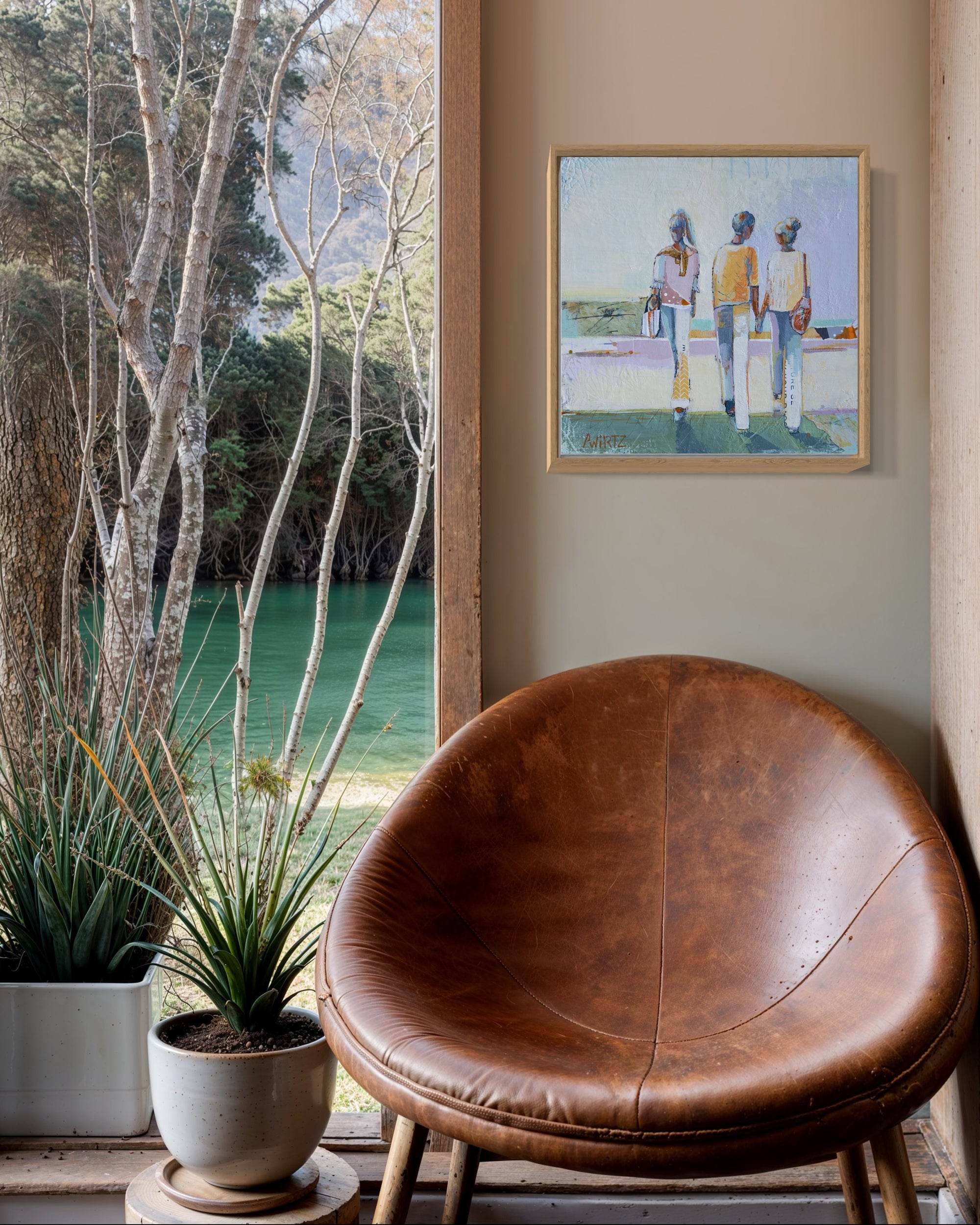 Brown leather chair in a room with a painting on the wall and a view of trees and water outside.